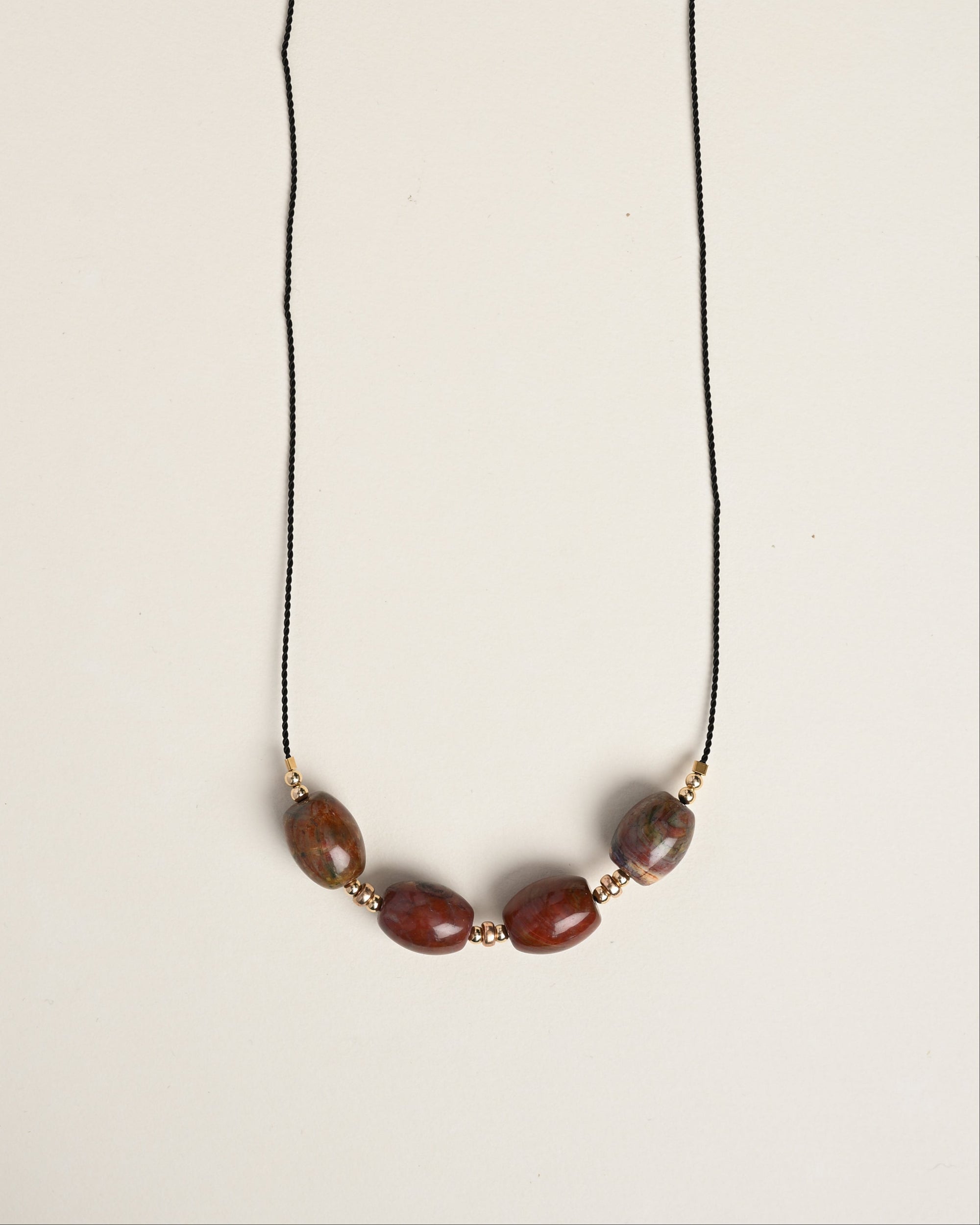 Necklace with brown beads on a thin black cord against a white background